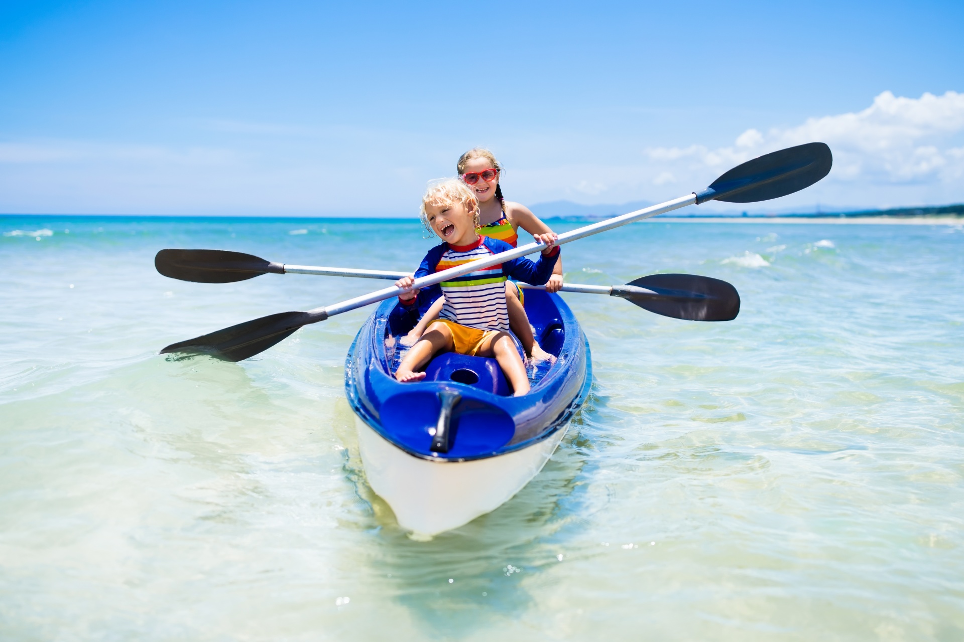 Kids kayaking in ocean. Children in kayak in tropical sea. Active vacation with young kid. Boy and girl in canoe on beautiful beach. Holiday activity with preschool child. Family summer fun.